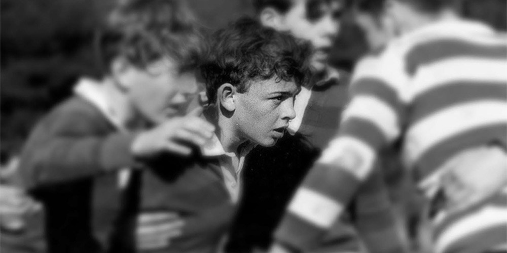 Black and white picture of children playing rugby in the 1970s
