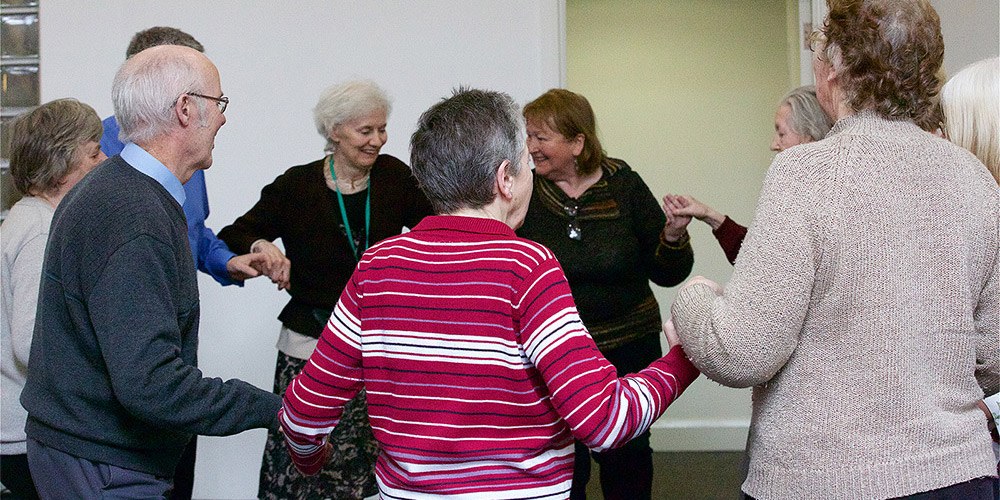 Older adult members holding hands and dancing in a circle