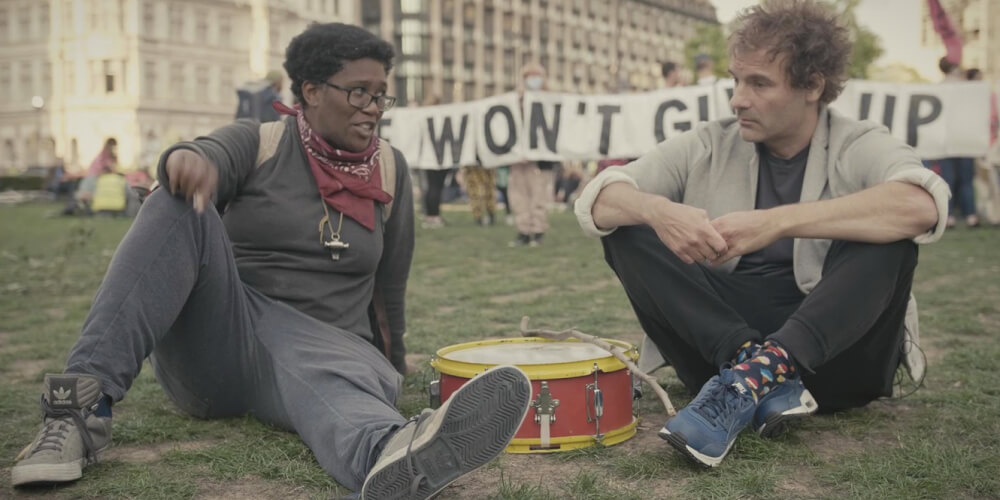 Alfie (left), a climate activist at an Extinction Rebellion protest sat with filmmaker Josh Appignanesi (right)