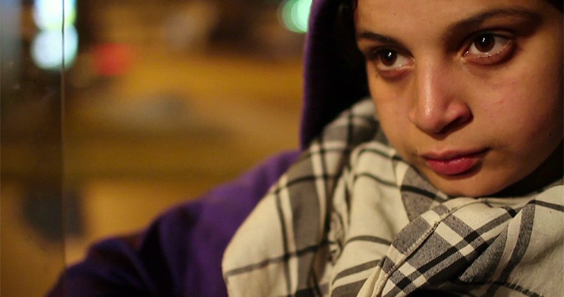 Close up of a young Arab female activist wearing a purple hoodie and black and white scarf