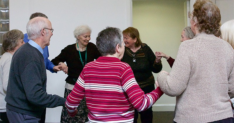 Older adult members holding hands and dancing in a circle