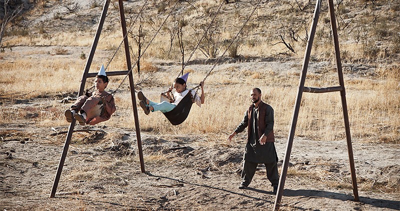 Father pushing children on swings