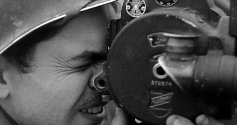 Close-up black and white picture of a soldier holding a film-camera from the 1940s