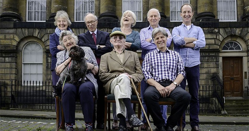 Eight participants of Secret History of our Streets sit in front of their homes